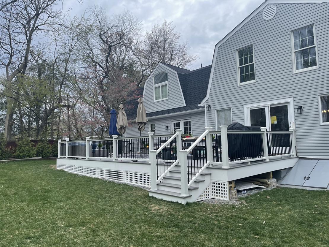 Completed white composite deck with railings, steps and lattice skirting