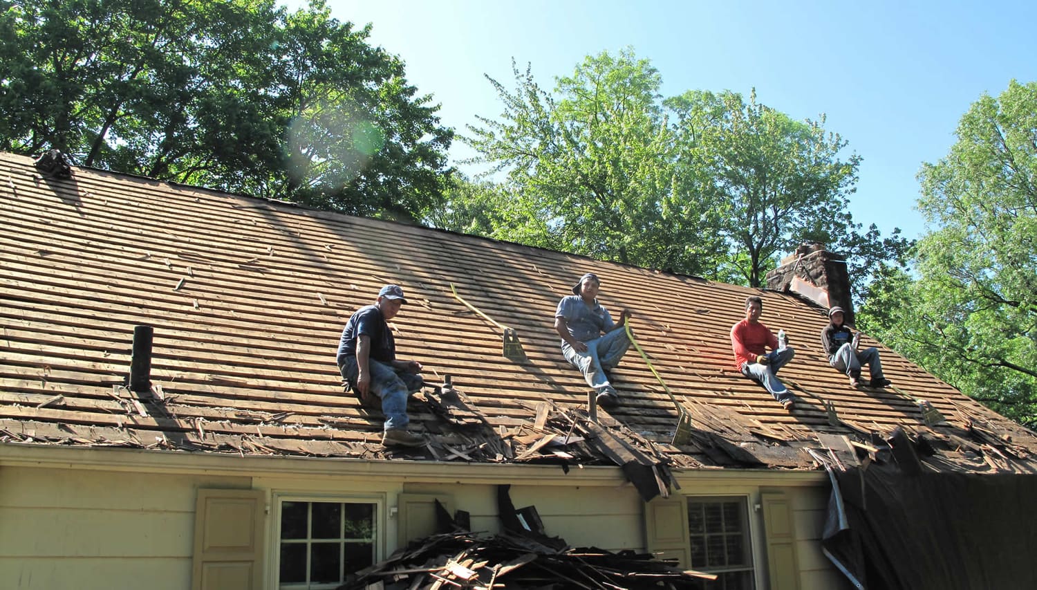 Roof tear-off in progress with crew on the deck